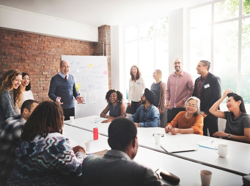 Coworkers around conference table with white board in background